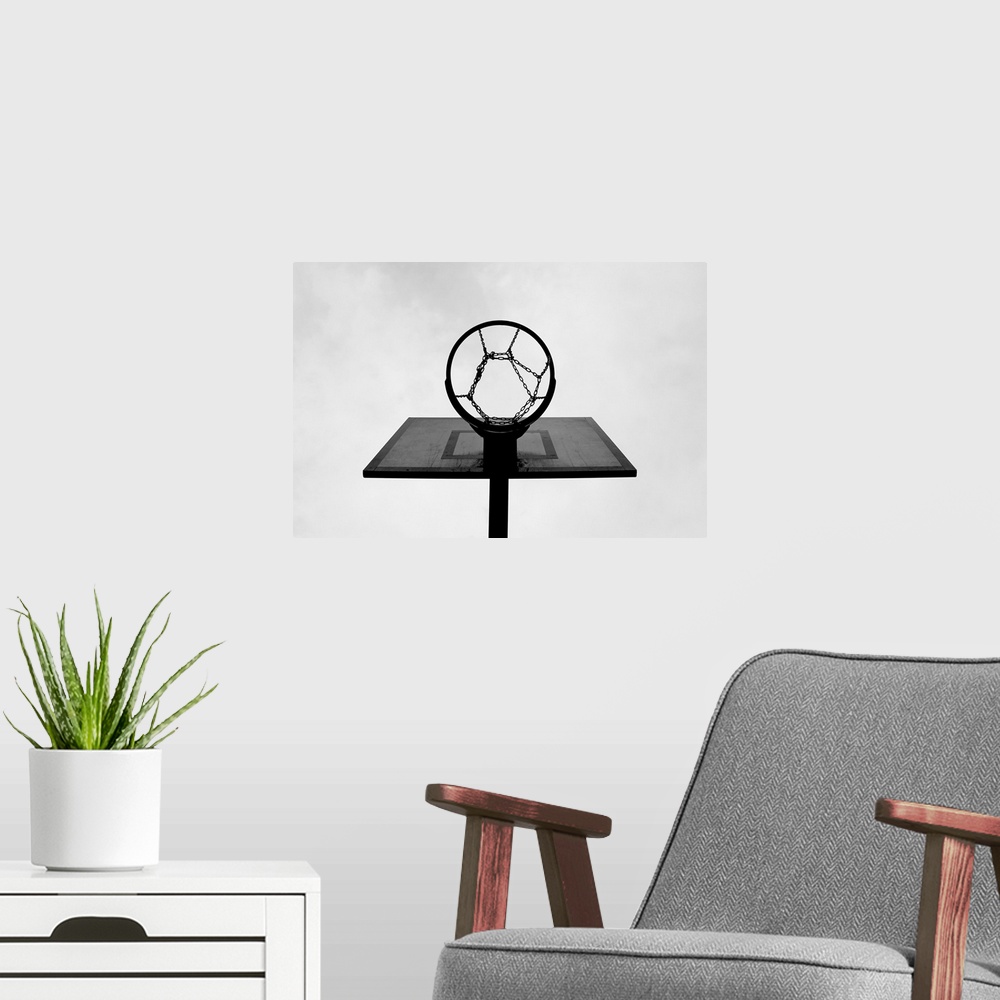 A modern room featuring This is a monochromatic, horizontal photograph taken from below an outdoor basketball hoop.