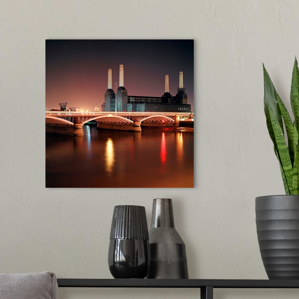 A modern room featuring Battersea Power Station at night with light reflections in river Thames.