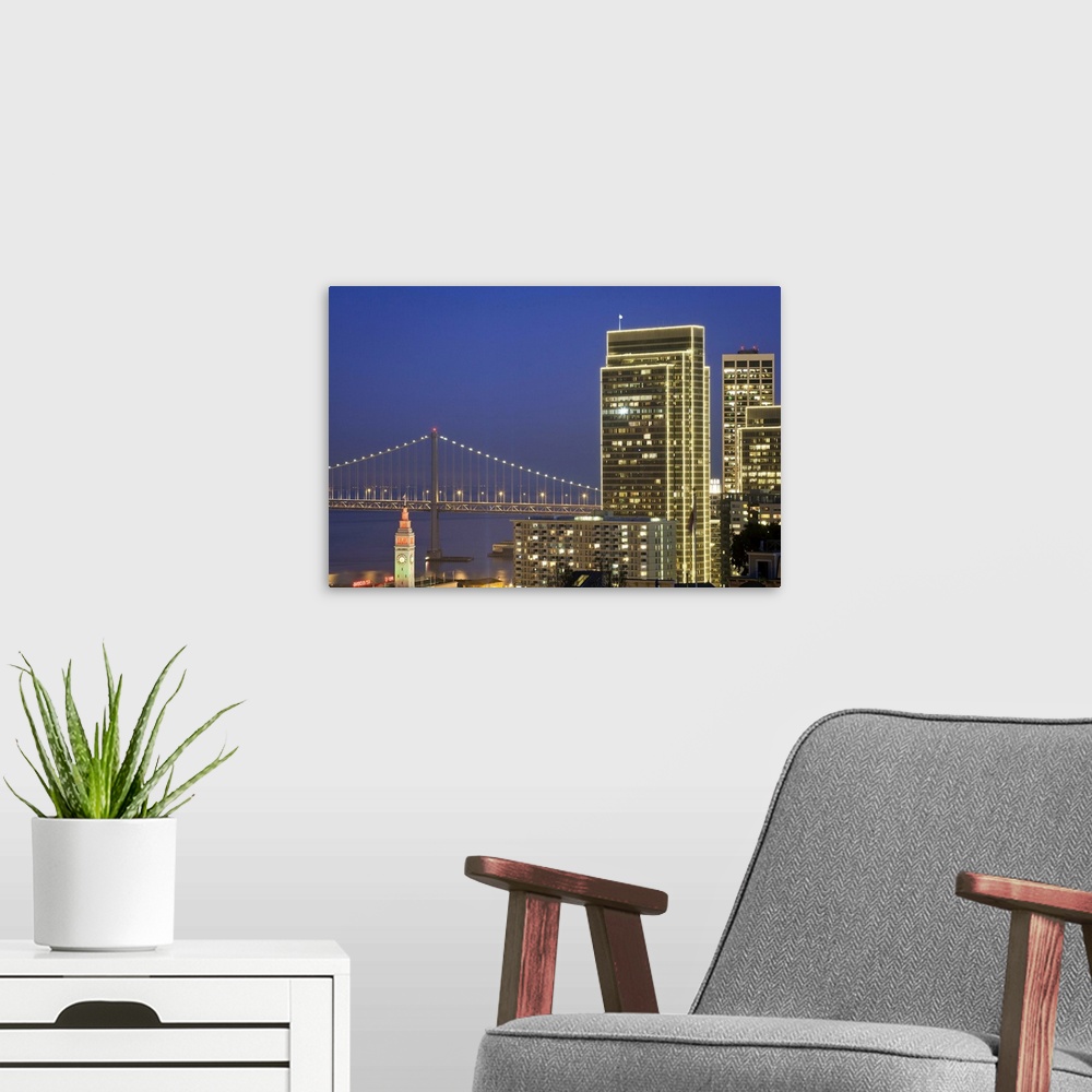 A modern room featuring Holiday lights are on downtown buildings, bay bridge and Ferry building in San Francisco.