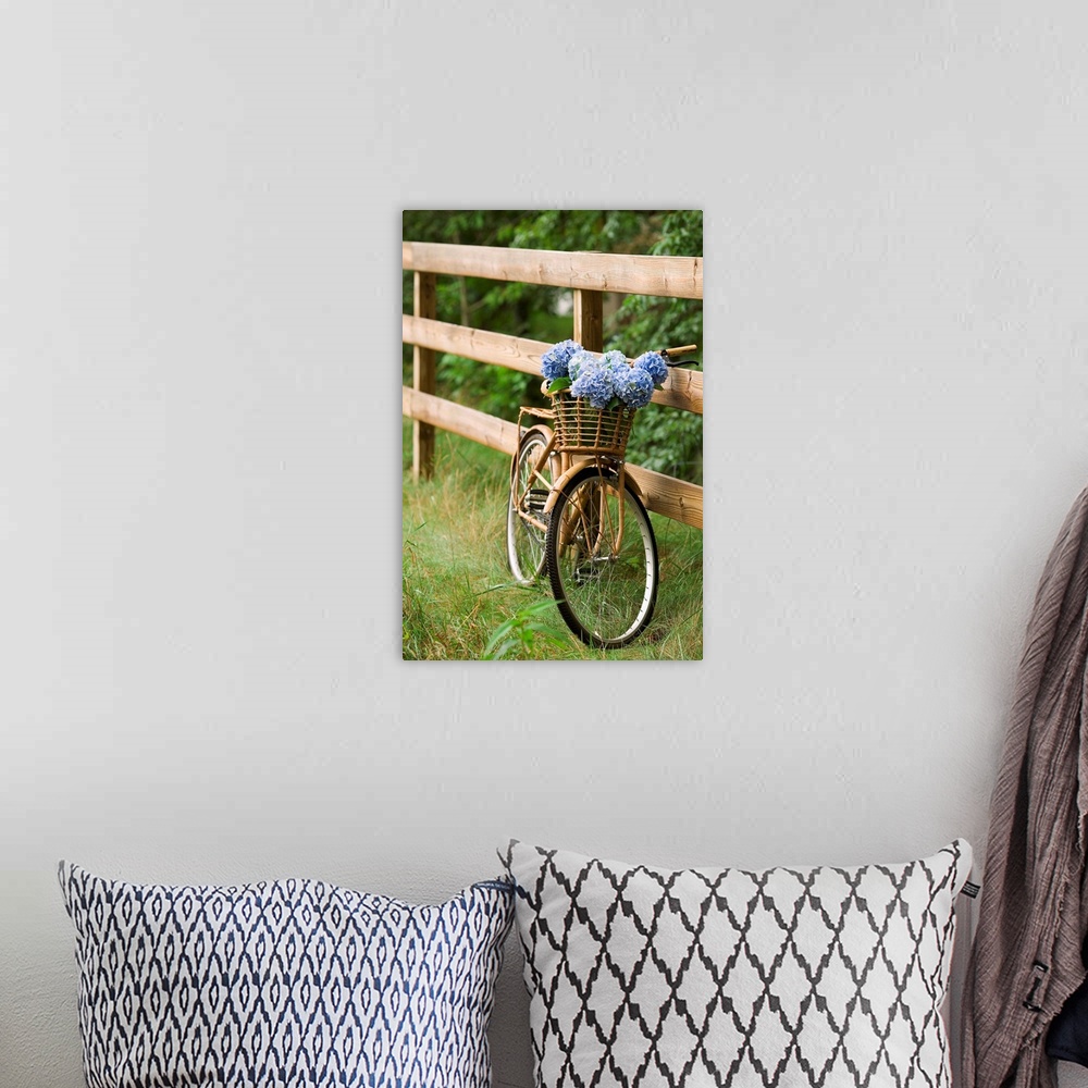A bohemian room featuring Photograph of vintage bicycle with a wooden basket filled with flowers leaning against a wooden f...