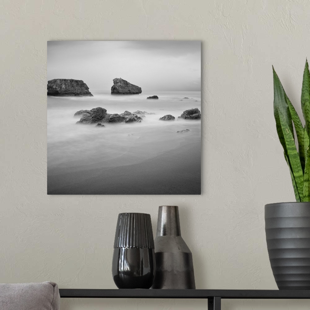 A modern room featuring Black and White image of rocks in the ocean near a sandy beach.
