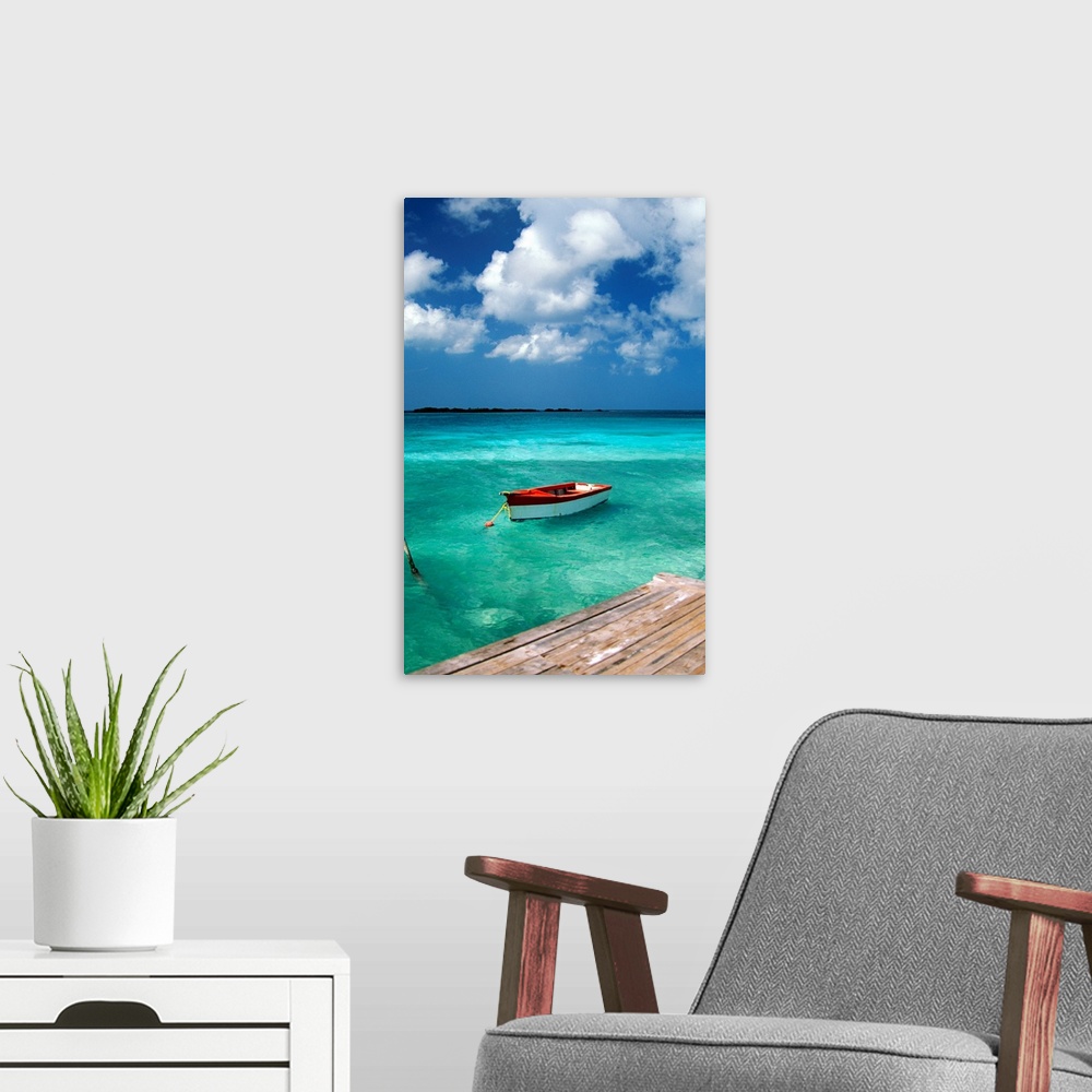A modern room featuring Huge photograph centers on a small water vessel sitting docked in the crystal clear waters next t...