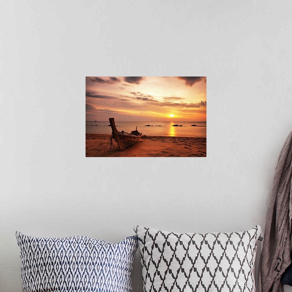 A bohemian room featuring A beautiful picture taken of a wooden boat sitting on the beach as the sun begins to set in the d...