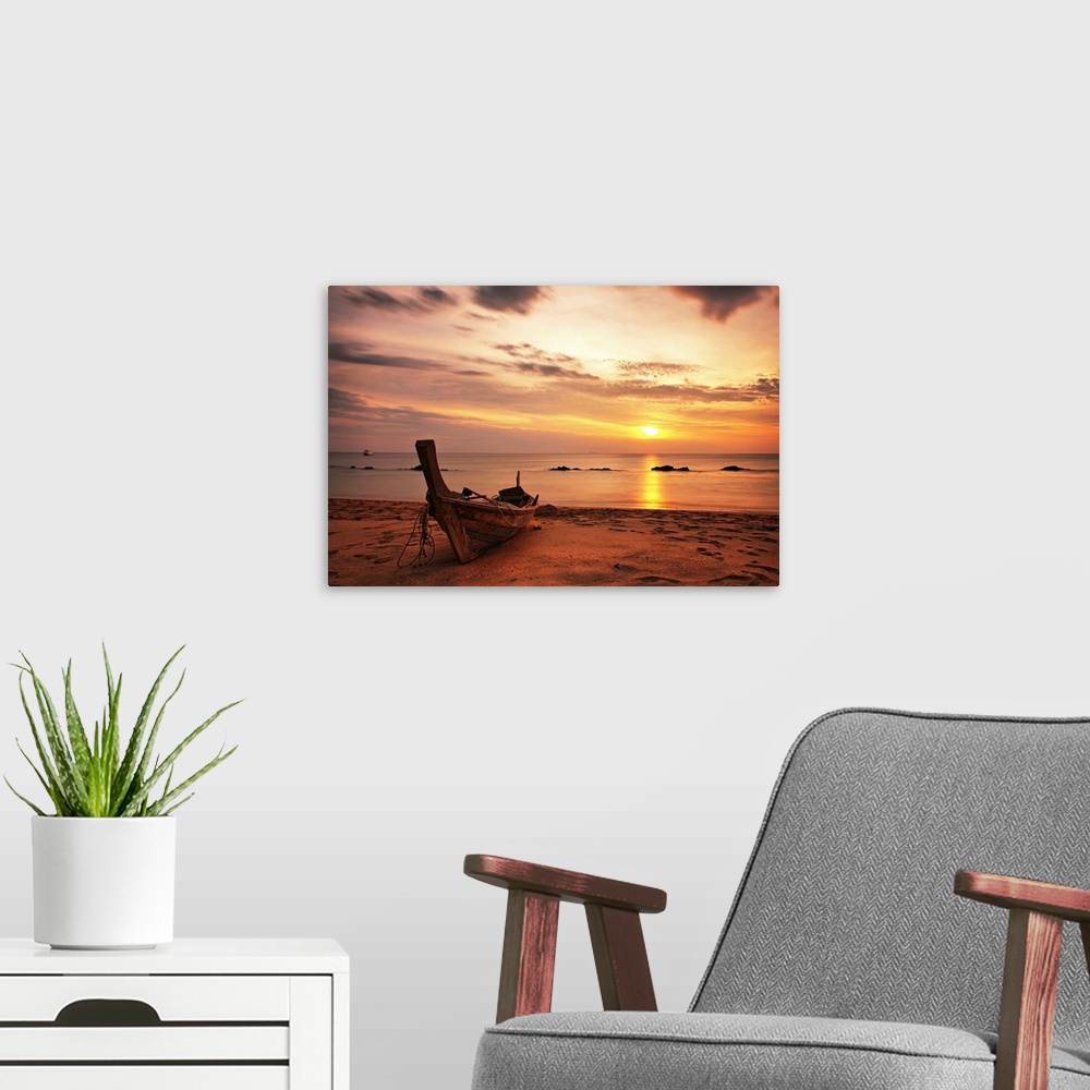 A modern room featuring A beautiful picture taken of a wooden boat sitting on the beach as the sun begins to set in the d...