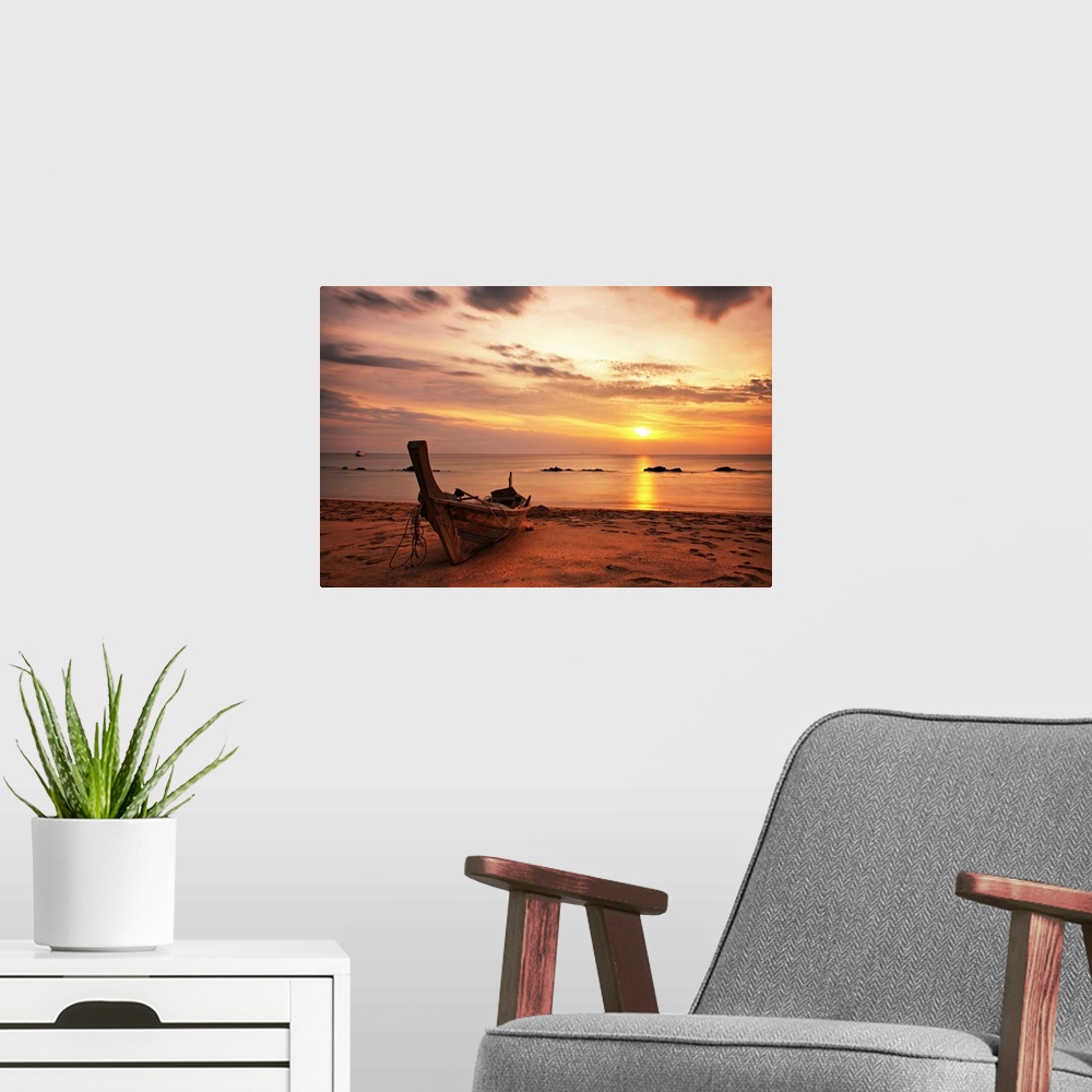 A modern room featuring A beautiful picture taken of a wooden boat sitting on the beach as the sun begins to set in the d...