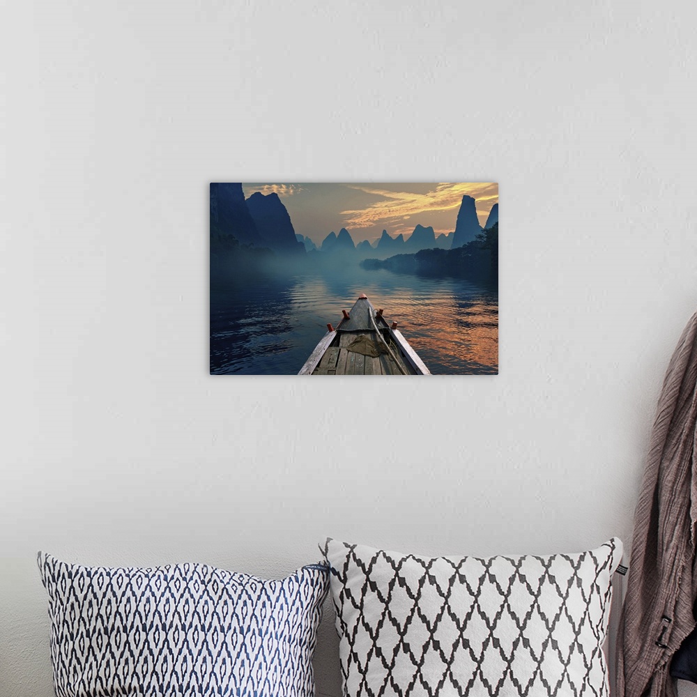 A bohemian room featuring A boat riding in a river during sunset next to a beautiful mountain.