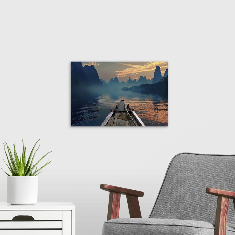 A modern room featuring A boat riding in a river during sunset next to a beautiful mountain.