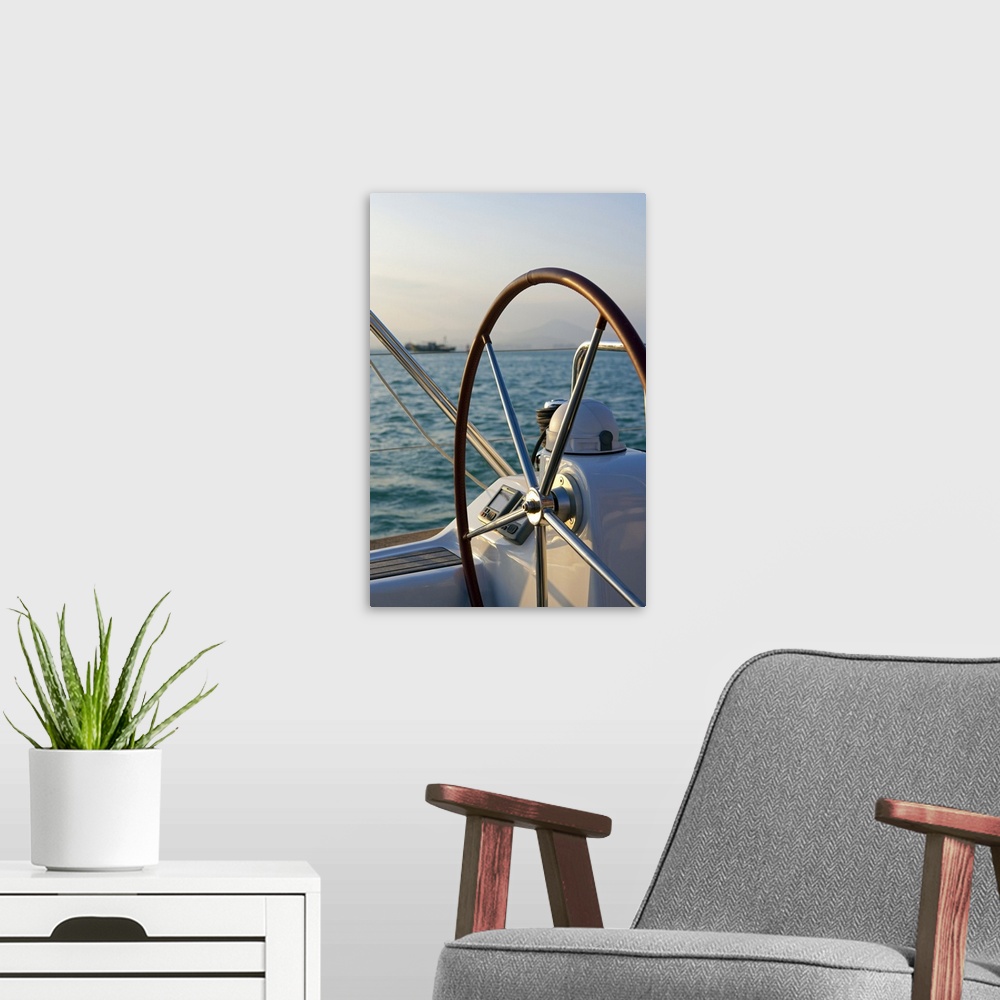 A modern room featuring Up-close photograph of steering wheel on sailboat with the ocean in the background.