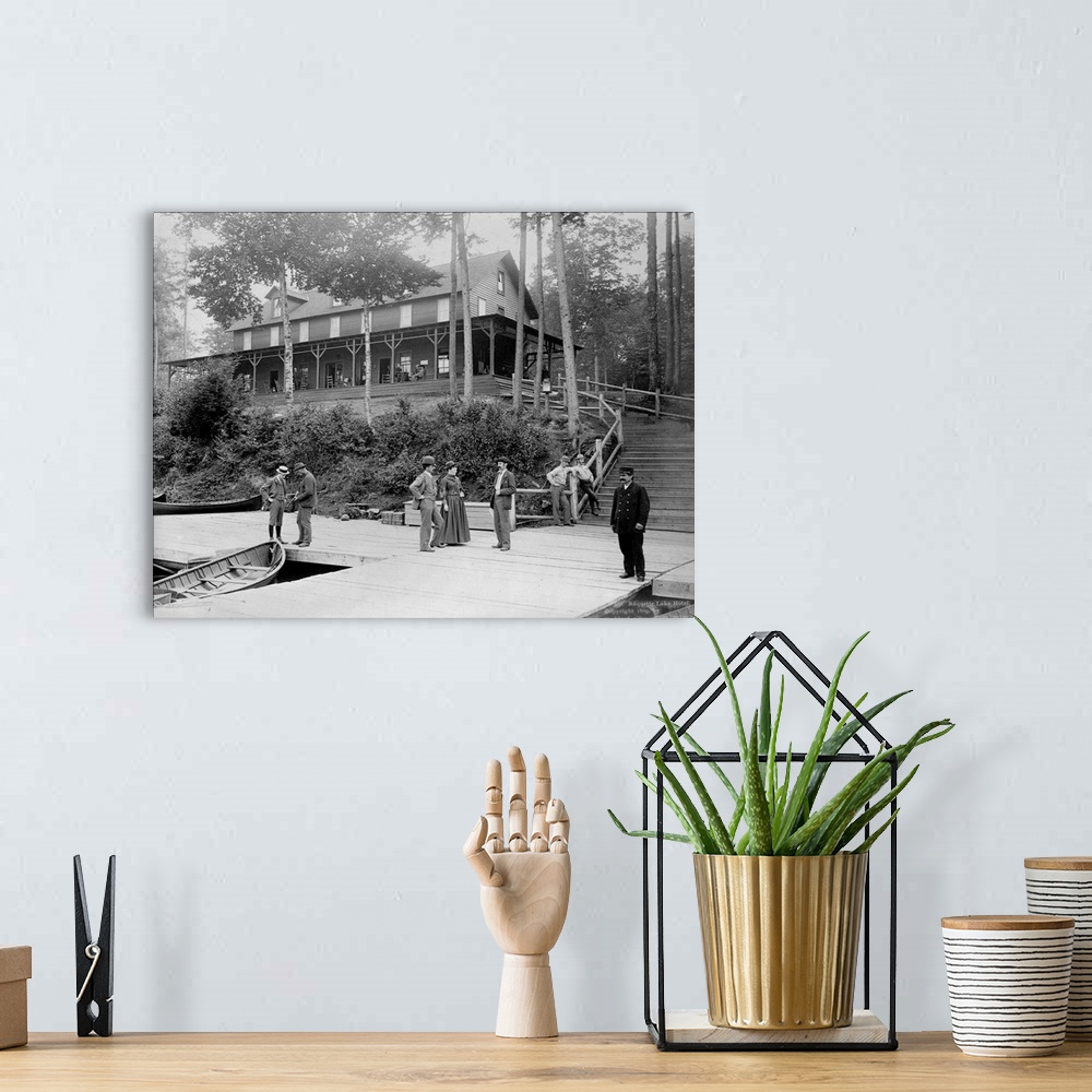 A bohemian room featuring Boaters vacationing in the Adirondack Mountains talk on the pier at the Raquette Lake Hotel. Ca. ...