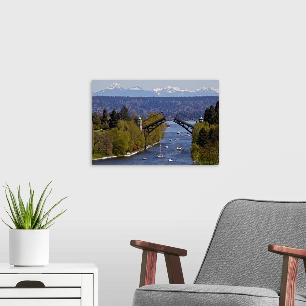 A modern room featuring Landscape photograph on a large wall hanging of Montlake drawbridge, raised as boats pass under i...