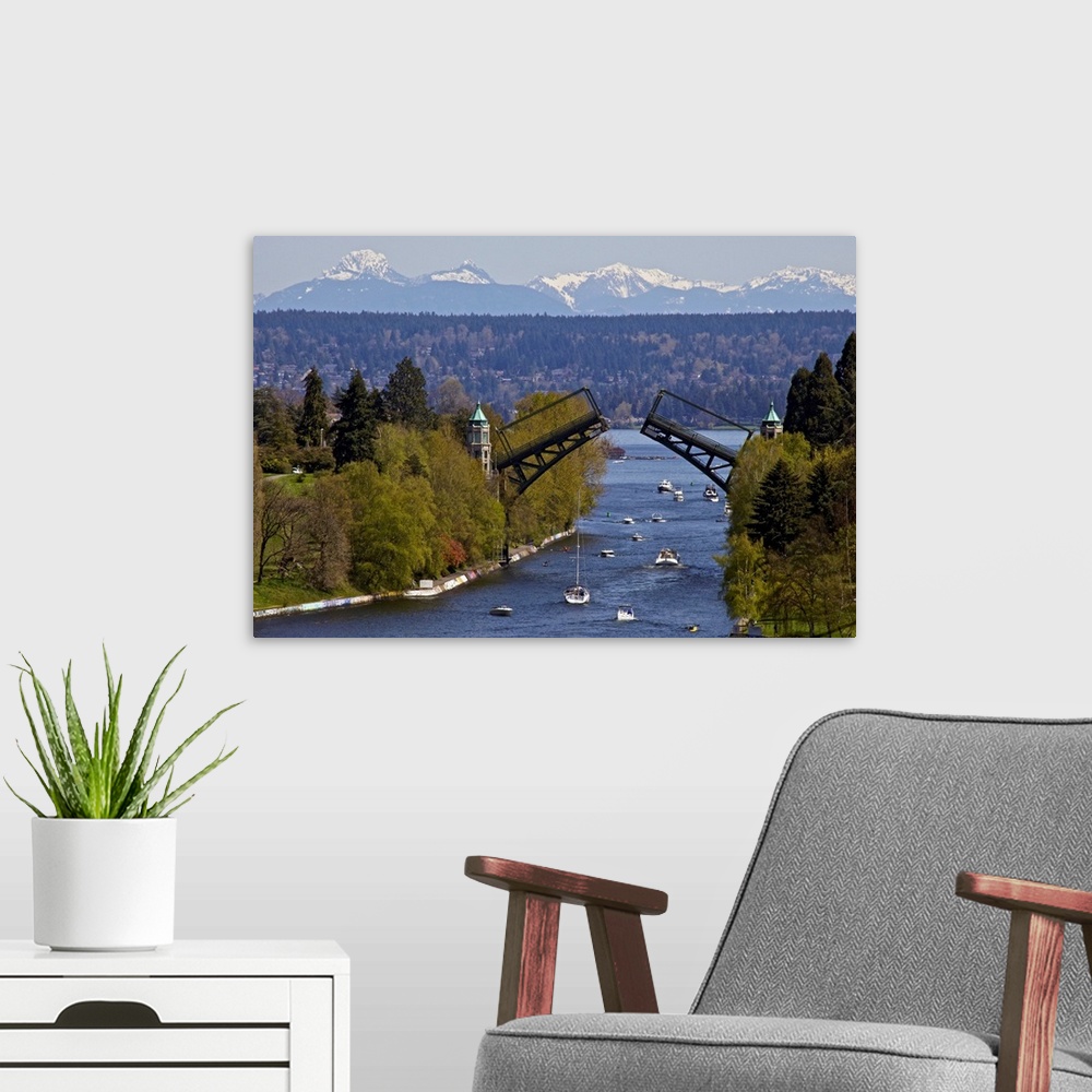 A modern room featuring Landscape photograph on a large wall hanging of Montlake drawbridge, raised as boats pass under i...