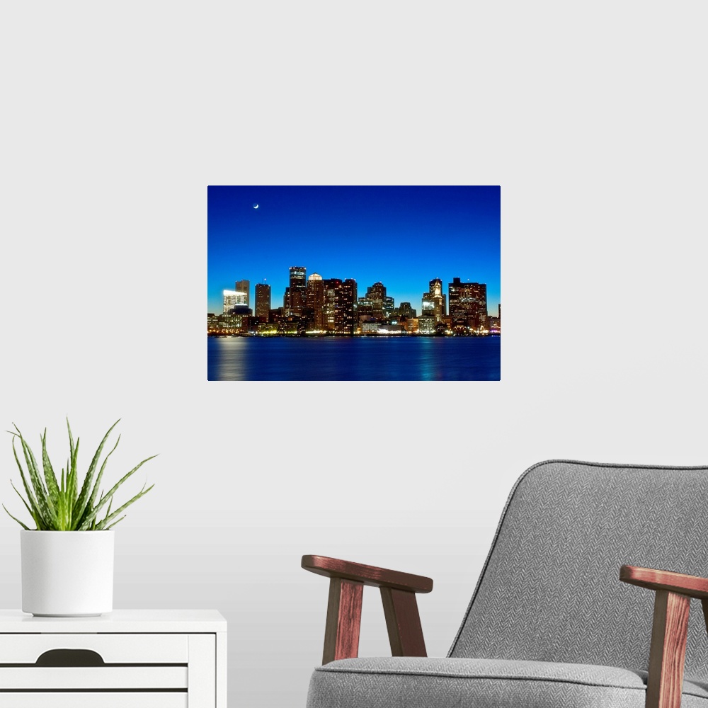 A modern room featuring This big photograph is of the Boston skyline under a night sky and crescent moon. Buildings are l...