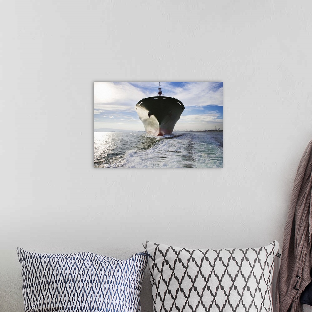A bohemian room featuring Bow view of cargo ship sailing out of port.
