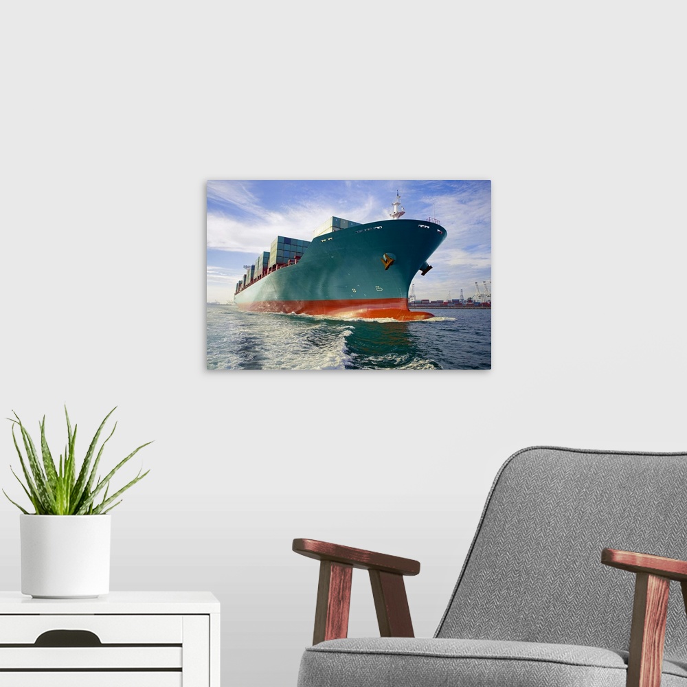 A modern room featuring This oversized photograph is taken while looking up at a large cargo ship that is headed out to sea.