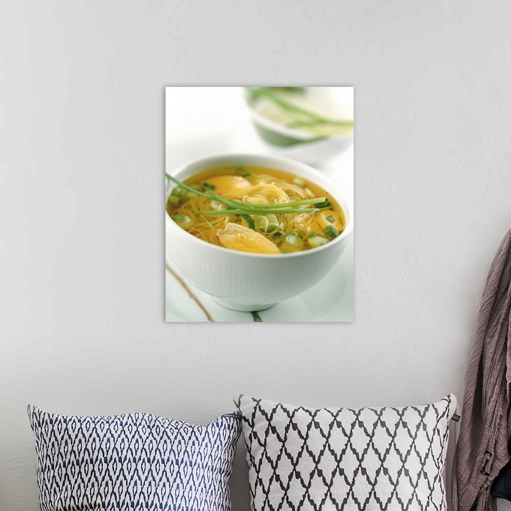 A bohemian room featuring Bowl of soup with noodles and bouillon, focus on foreground