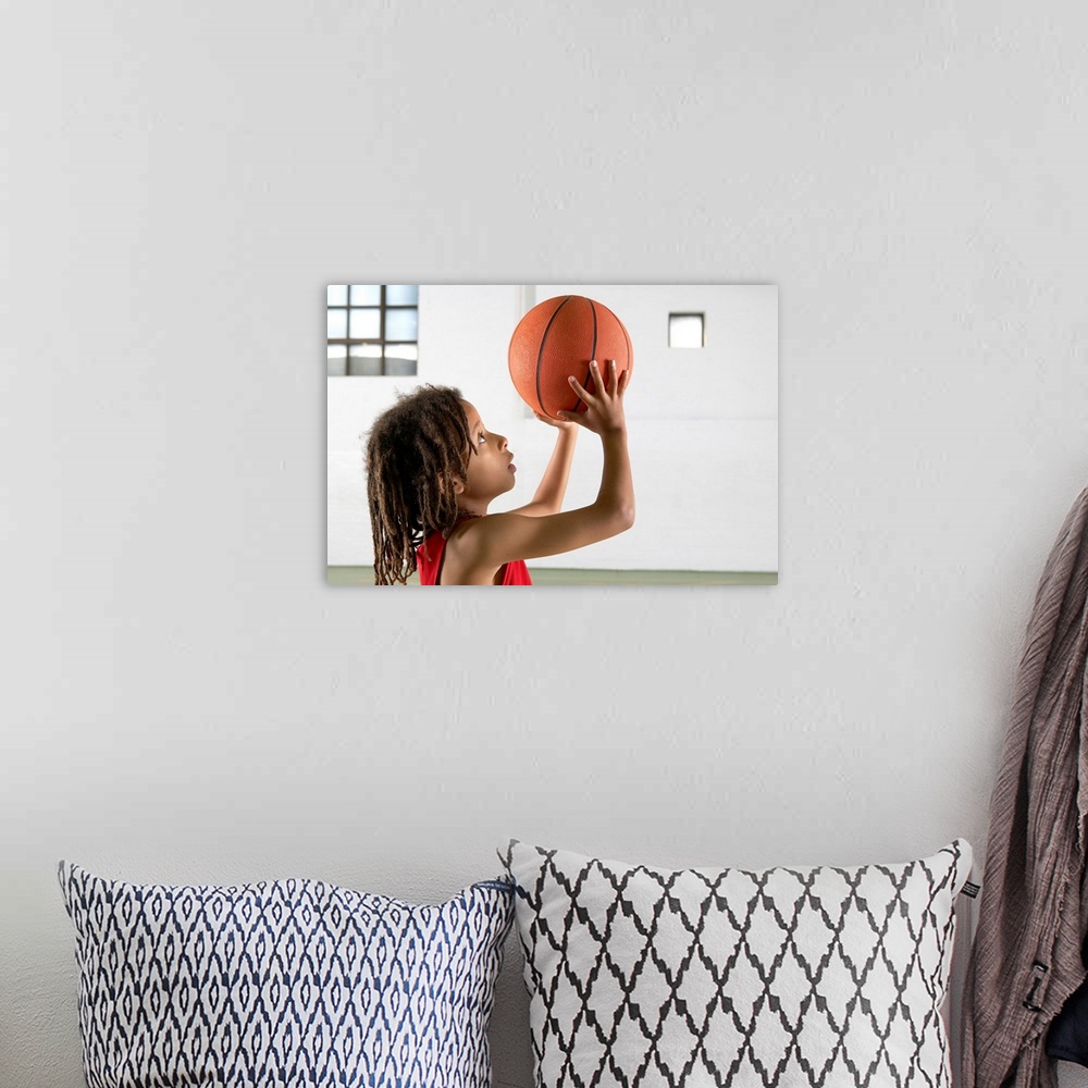 A bohemian room featuring Boy aiming a shot with a basketball in a school sports hall.