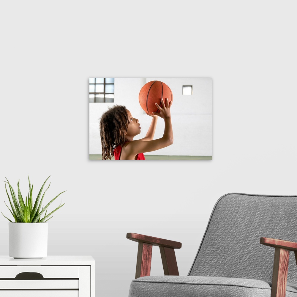 A modern room featuring Boy aiming a shot with a basketball in a school sports hall.