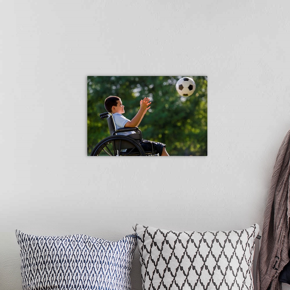 A bohemian room featuring Hispanic boy, 8, in wheelchair with soccer ball
