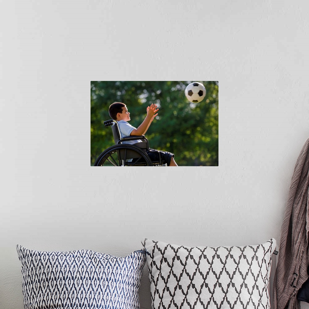 A bohemian room featuring Hispanic boy, 8, in wheelchair with soccer ball