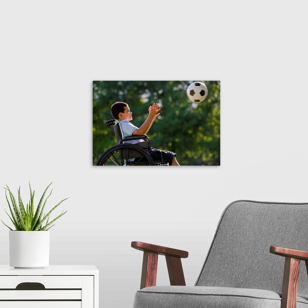 A modern room featuring Hispanic boy, 8, in wheelchair with soccer ball
