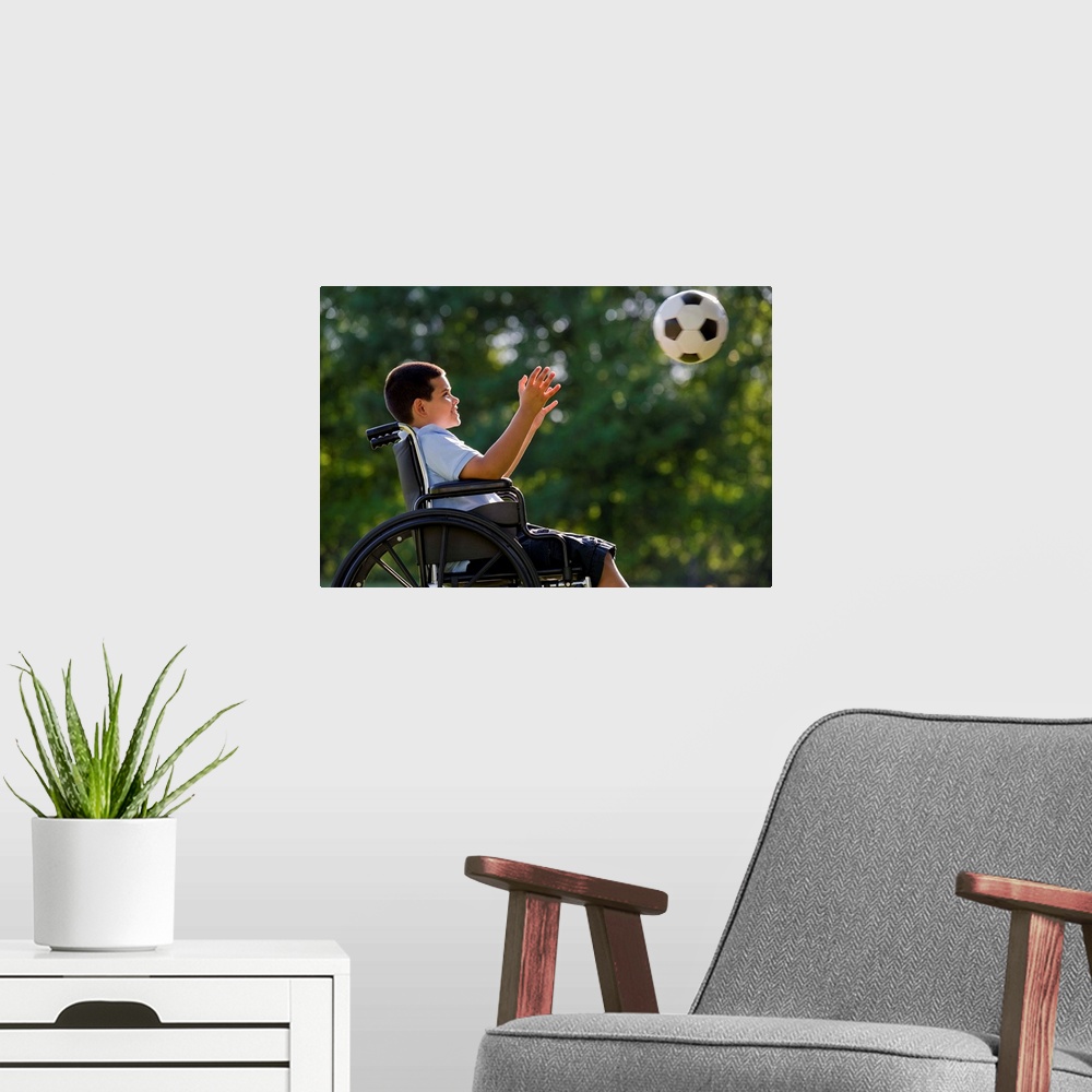 A modern room featuring Hispanic boy, 8, in wheelchair with soccer ball