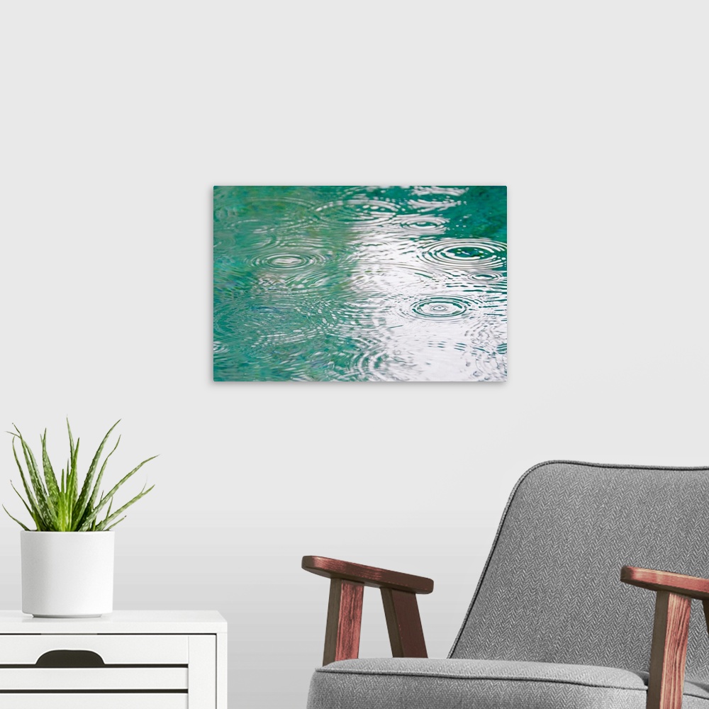 A modern room featuring A photograph is taken of ripples in water as rain hits it.
