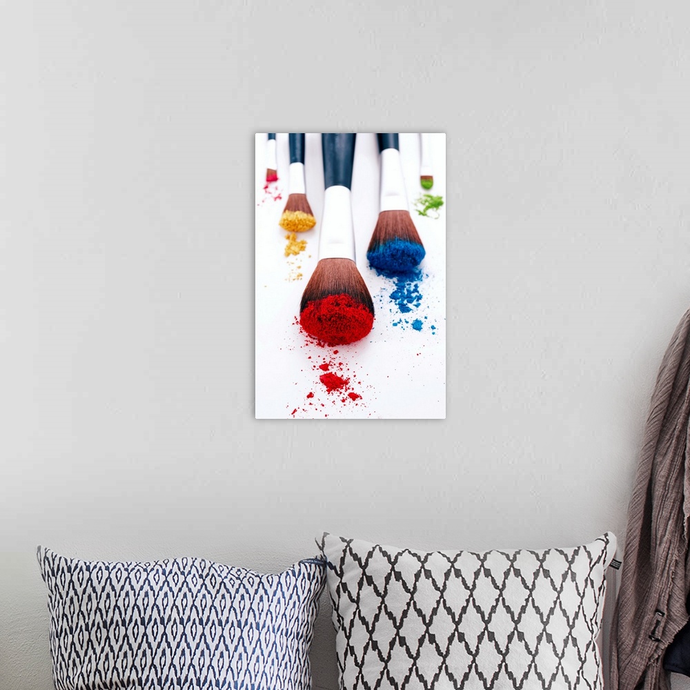 A bohemian room featuring A vertical photo of makeup brushes heavily filled with pigment resting on blank a surface.