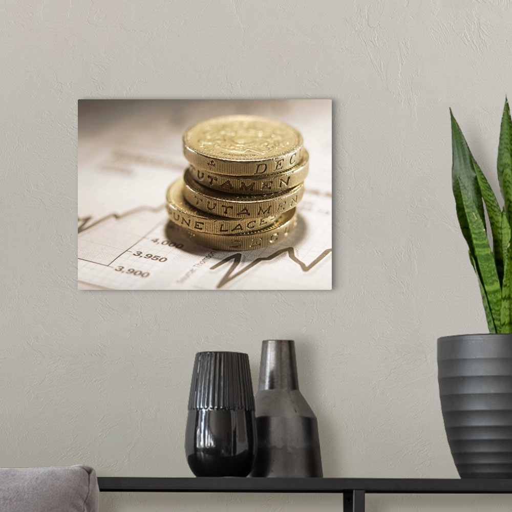 A modern room featuring British Currency: Stacked pound coins on financial graphs, close-up