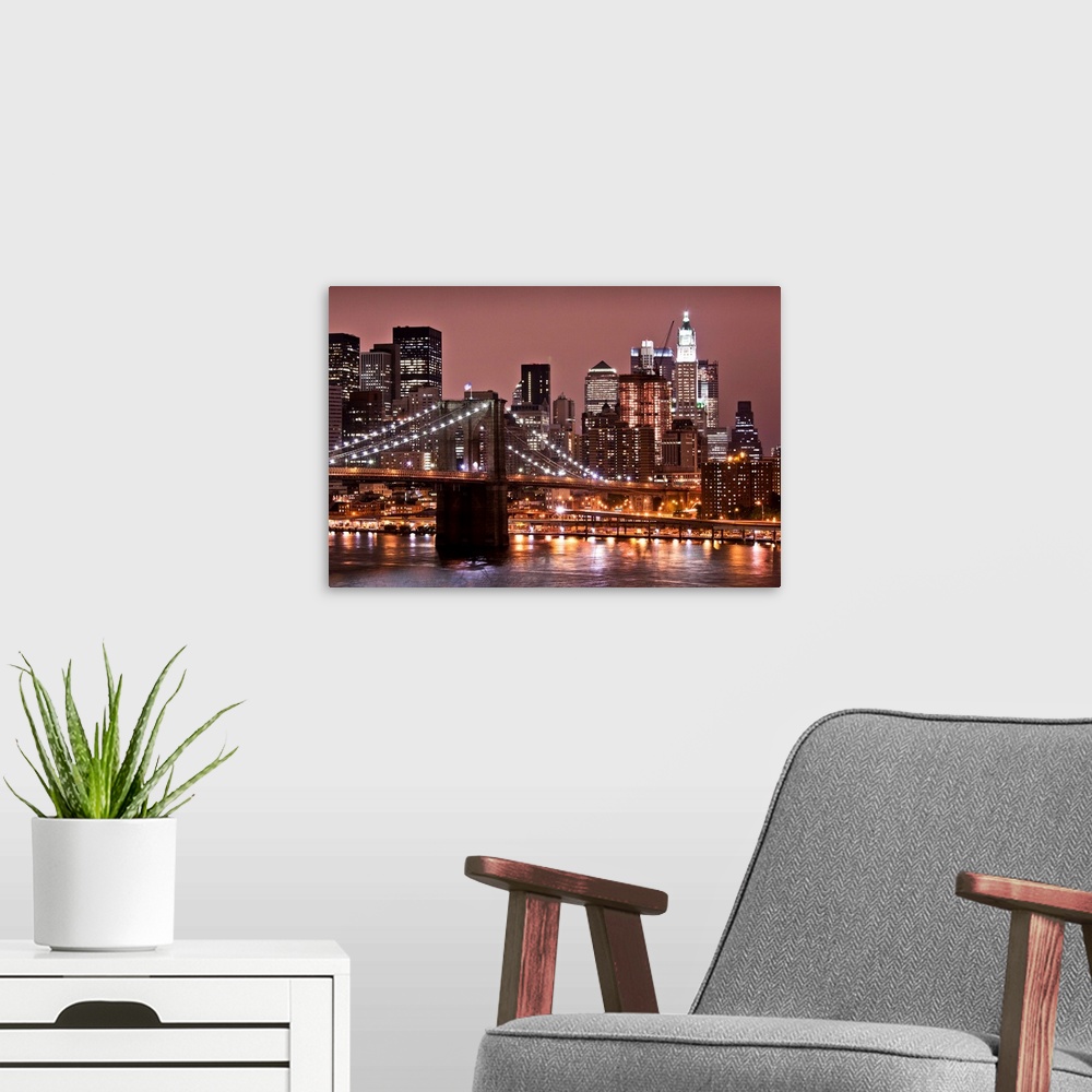 A modern room featuring USA, New York, Brooklyn, Brooklyn Bridge at night and East River with Lower Manhattan skyline glo...
