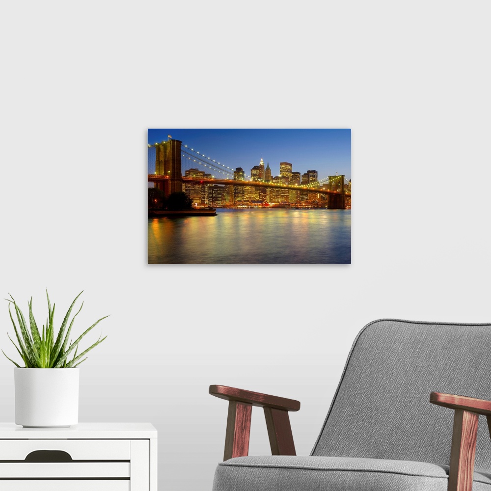 A modern room featuring Photograph of skyline and waterfront after sunset.  The buildings lights are reflected in the wat...