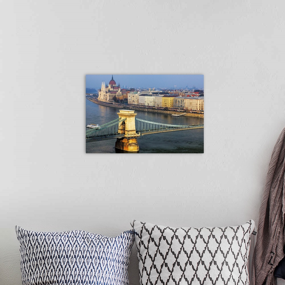 A bohemian room featuring Warm sunlight spotlights the Chain Bridge and the Hungarian Parliament Building against a blue sk...