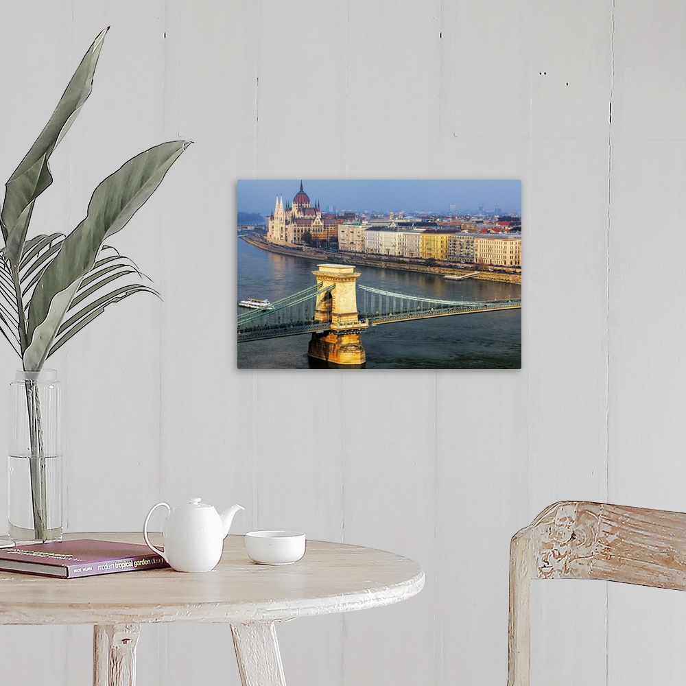 A farmhouse room featuring Warm sunlight spotlights the Chain Bridge and the Hungarian Parliament Building against a blue sk...