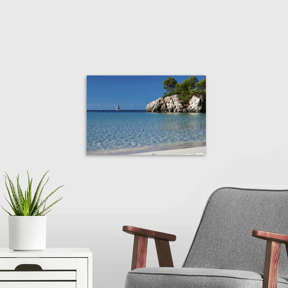 A modern room featuring Photo of crystal clear blue water and white sand beach in Spain with a sailboat in the distance a...