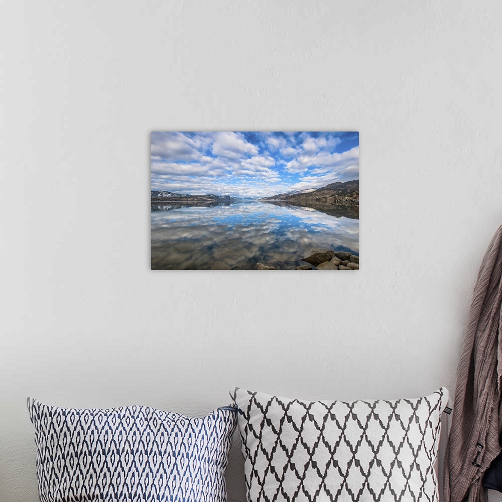 A bohemian room featuring Late winter reflections of surrounding mountains and scattered clouds are mirrored in Okanagan lake.