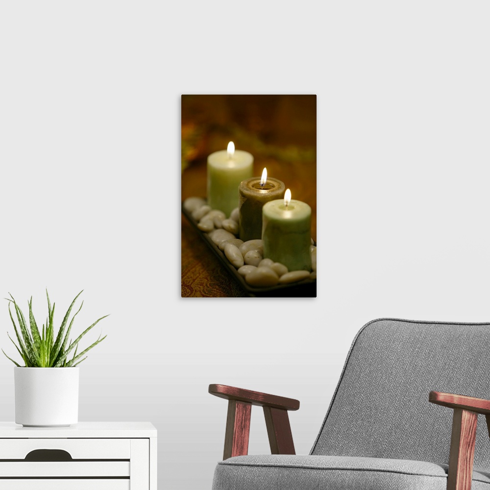 A modern room featuring Relaxing photograph of three lit candles resting in a shallow dish of round, polished pebbles.