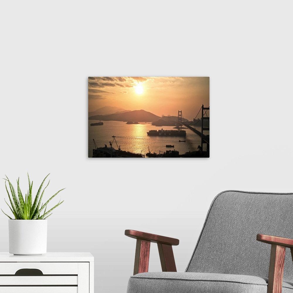 A modern room featuring Cargo vessel crossing the bridge at sunset.