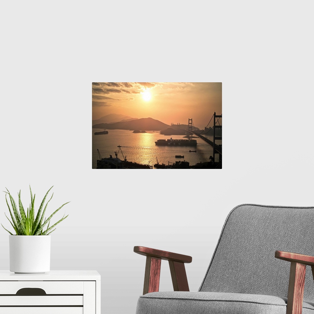 A modern room featuring Cargo vessel crossing the bridge at sunset.