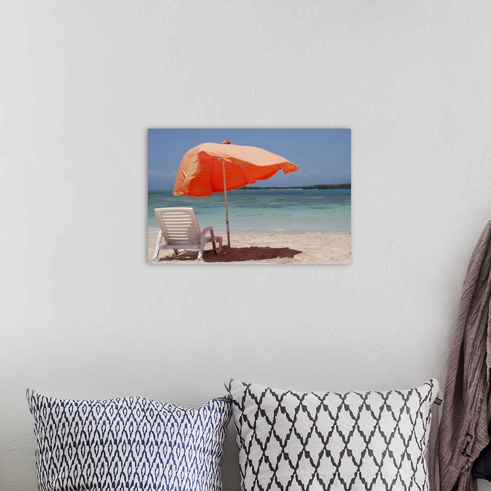 A bohemian room featuring Close-up of relaxing chair with parasol umbrella on beach.