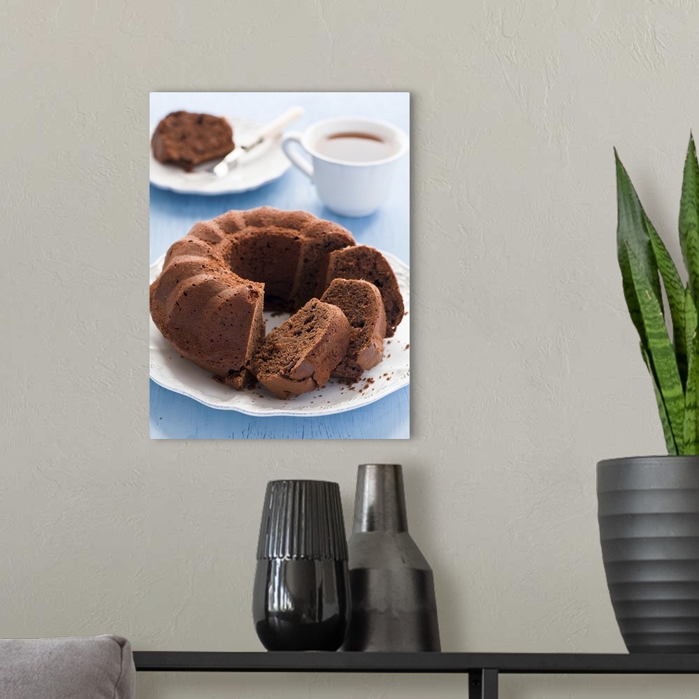 A modern room featuring Chocolate cake in white plate and cup of tea.