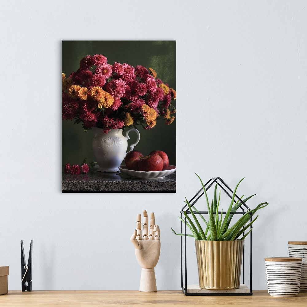 A bohemian room featuring Chrysanthemums flowers in vase with red apples in plate.