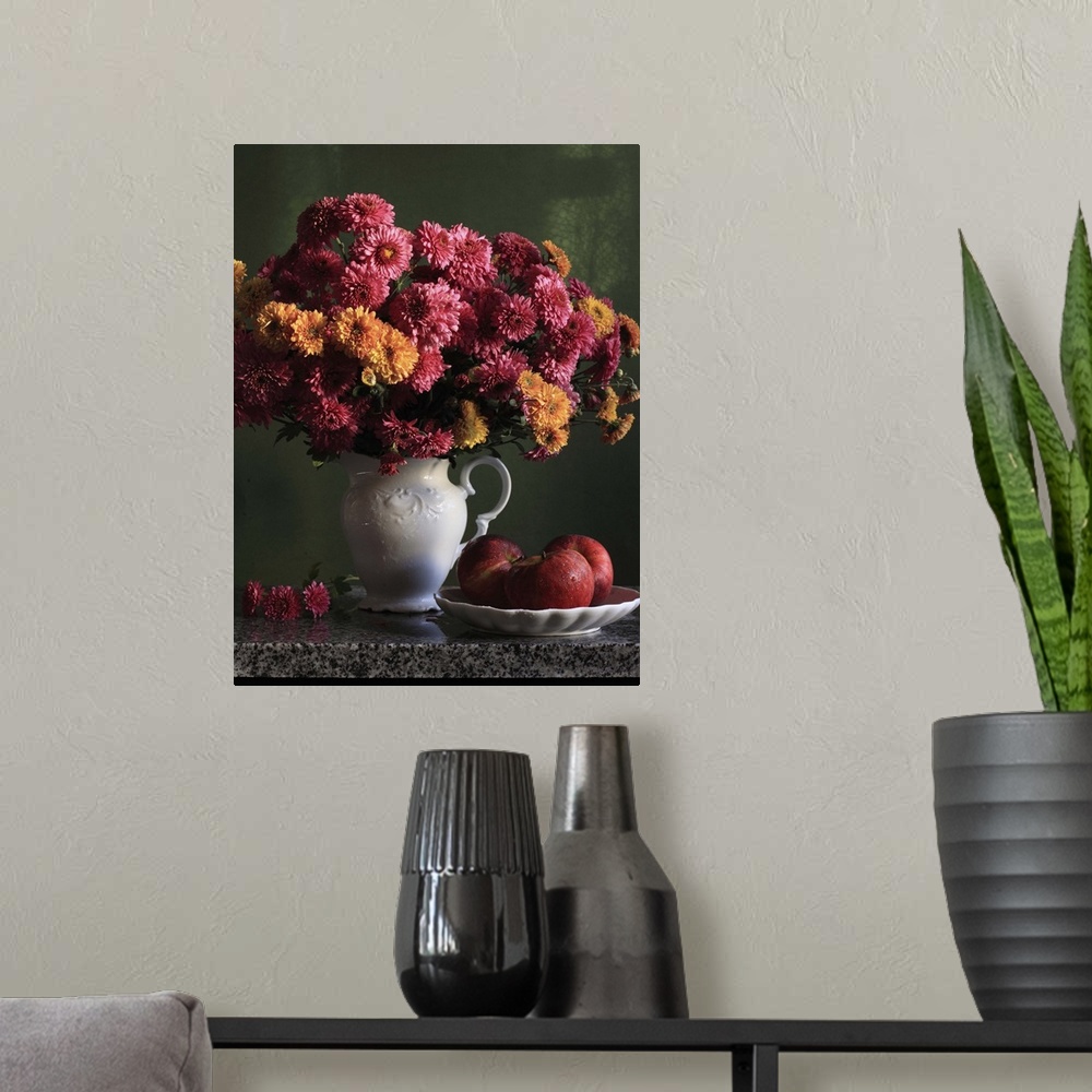 A modern room featuring Chrysanthemums flowers in vase with red apples in plate.