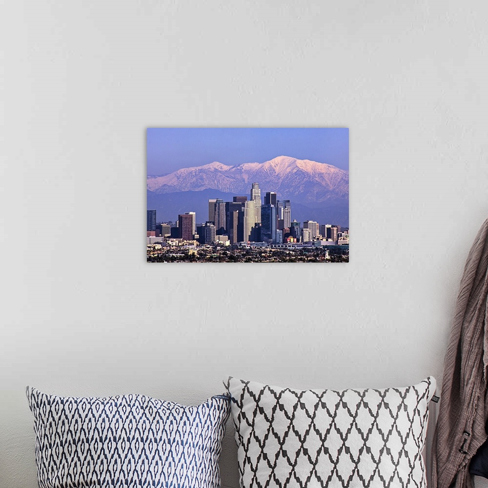 A bohemian room featuring This large piece is a photograph large buildings in Los Angeles with big snow covered mountains i...