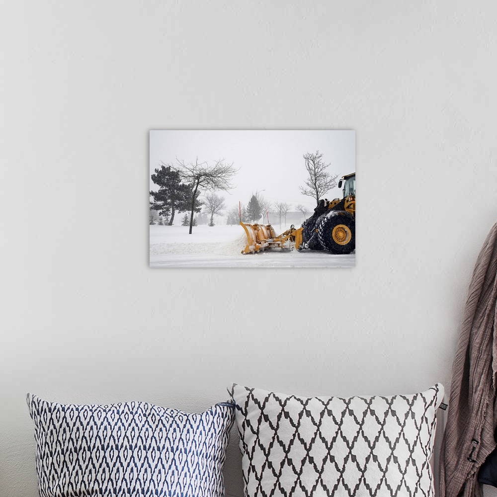A bohemian room featuring A snow plow / tractor clearing the snow on the roads from a winter storm.