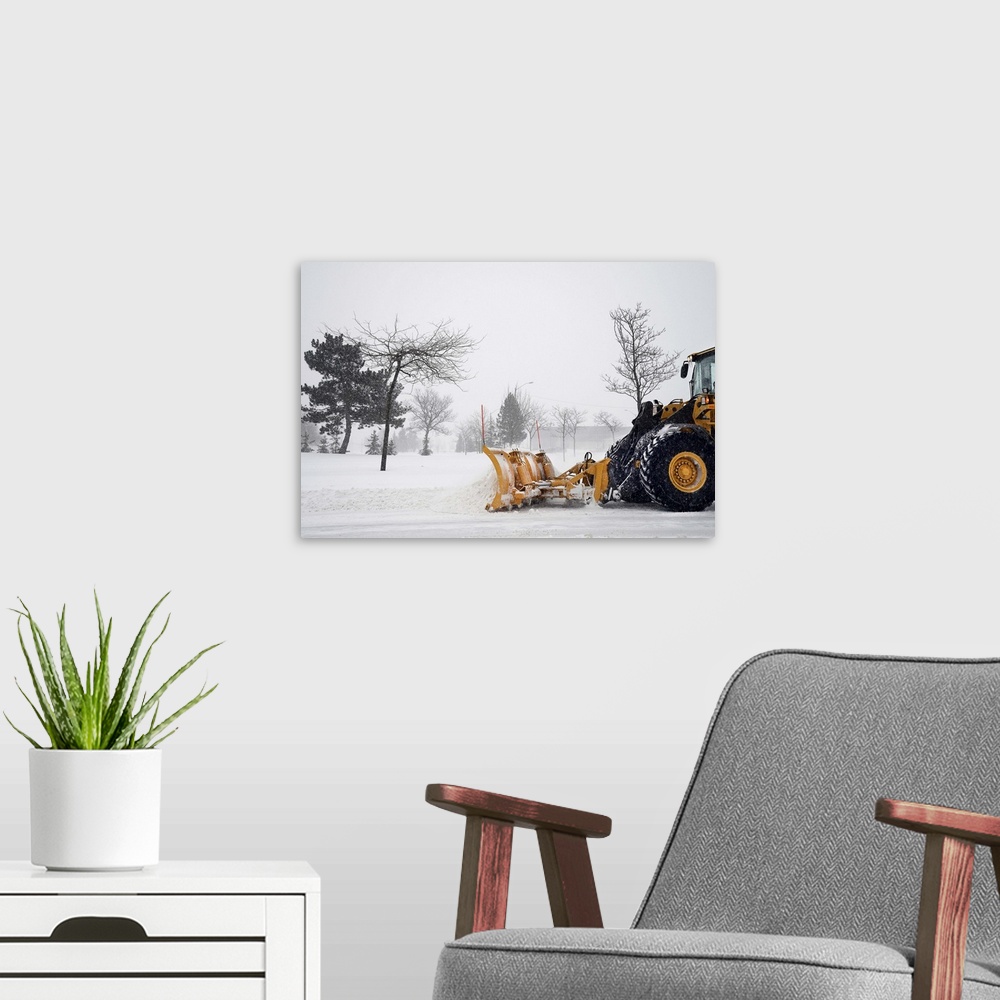 A modern room featuring A snow plow / tractor clearing the snow on the roads from a winter storm.