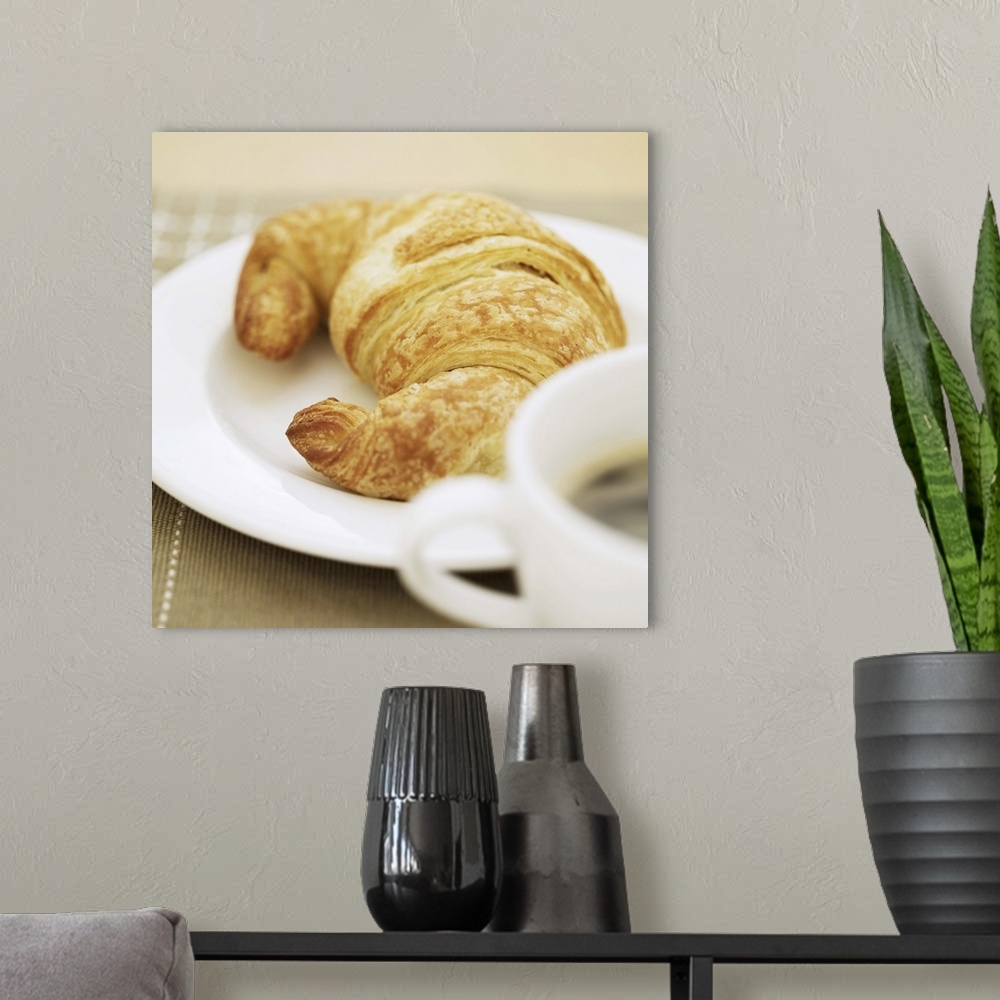 A modern room featuring close-up of a cup of hot black coffee and a croissant