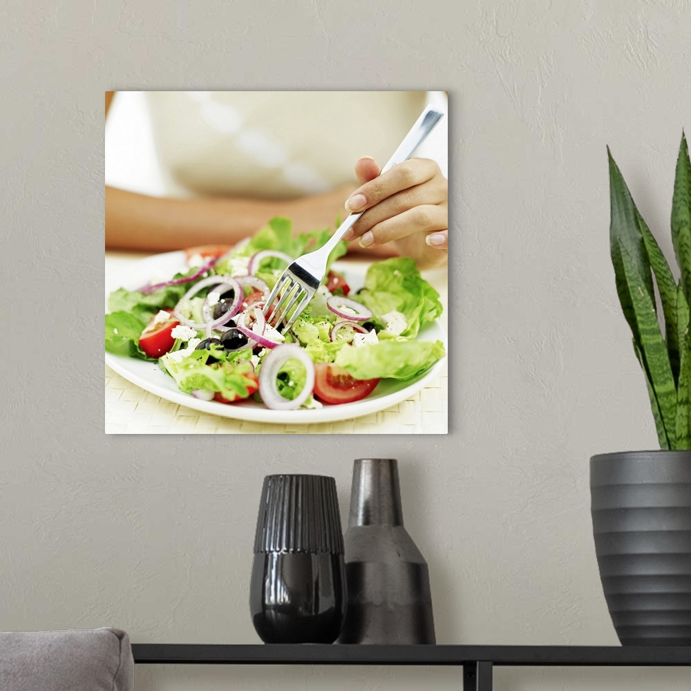 A modern room featuring Close-up of a person eating salad with a fork