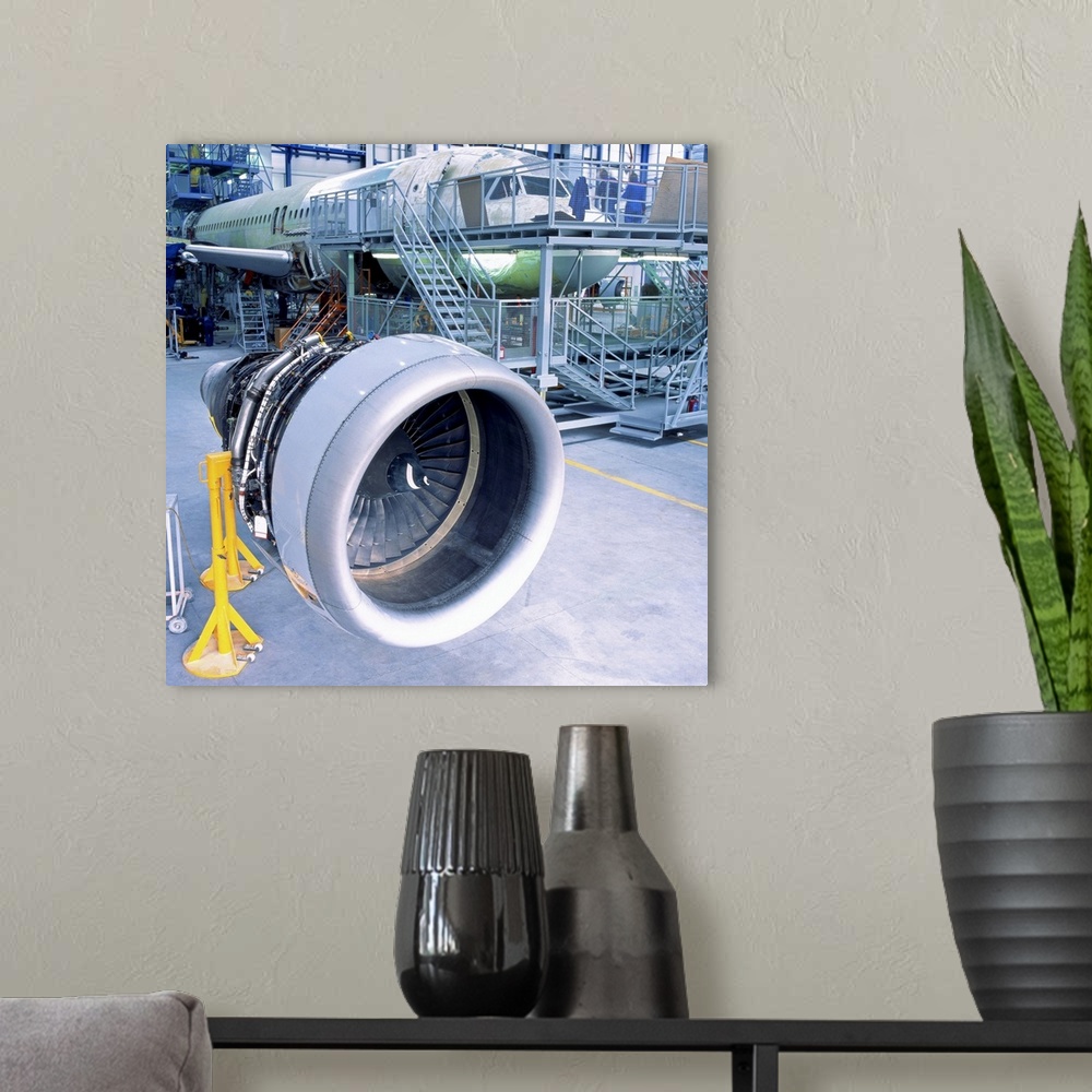 A modern room featuring close-up of an aircrafts engine turbine kept in a hanger for assembly