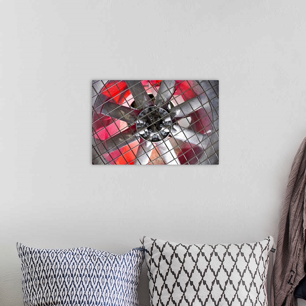 A bohemian room featuring Close-up of an industrial ventilation fan with red hues lighting up the back.