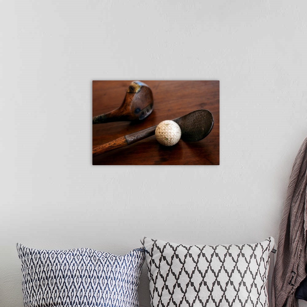 A bohemian room featuring Horizontal photograph on a large canvas of two antique golf clubs and a ball, lying on a wooden t...