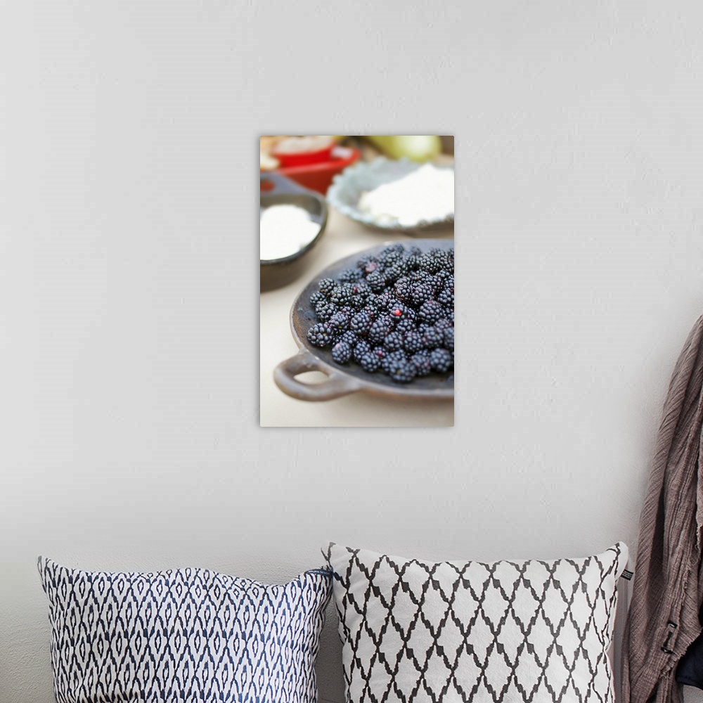 A bohemian room featuring Close up of bowl of blackberries on a table with bowls of cheese and breads in the background.